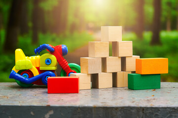Naklejka premium toy motorcycle and toy house made of wooden cubes on nature background
