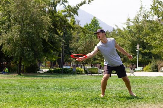 Young man playing with frisbee on sunny day at the park. Sports activity, recreation concepts