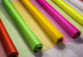 Row of various rainbow colored textile..Rolls of colored wrapping organza ribbons.