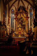 Fototapeta na wymiar Decorative interior of church St. Henry and St. Kunhuty, gilded ornamented baroque main altar, gothic stained glass windows, marble statues, wood carved benches, Prague, Czech Republic