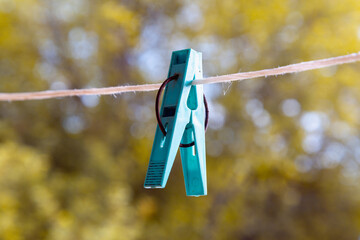 Plastic clothespin on a rope on the background of the forest.