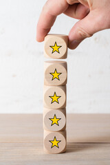 hand stacking cubes with star symbols on wooden background - 437621750