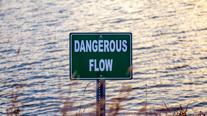 Dangerous Flow warning sign next to lake