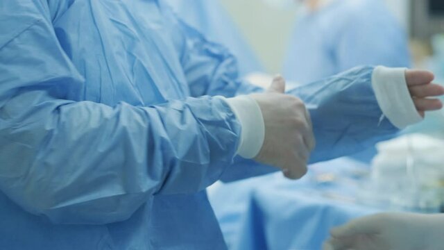 The surgeon prepares for the operation, fastens the sterile gown in the modern operating room.
