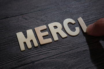 Merci, thank you in french, text words typography written with wooden letter on black background, life and business motivational inspirational