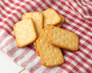 Cracker cookies with tablecloth on white wooden table background.
