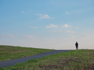堤防の土手を歩く男性