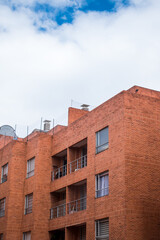 Brick building with some windows and some balconies with blue sky as background