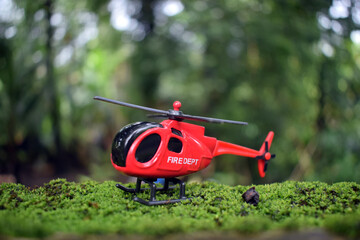 Toy fire department red colour helicopter landed on a green moss plants