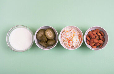 Healthy probiotics food on light green background. Sauerkraut, pickled cucumbers, natural yogurt and almond. Fermented foods for digestion and microbiome intestine. Top view, flat lay