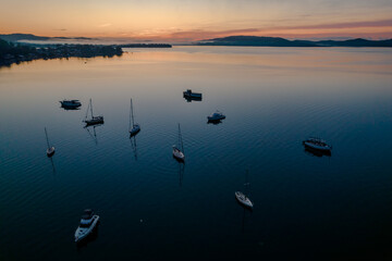 Obraz na płótnie Canvas Sunrise waterscape with boats, light cloud and fog