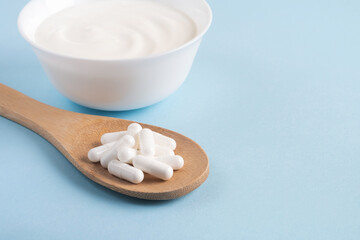 Homemade yogurt with probiotics and capsules pills on a wooden spoon. Fermented foods, dairy,...