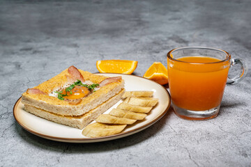 Modern breakfast, toasted bread, eggs, bacon, served with fresh orange juice on a cement floor. Good healthy food.