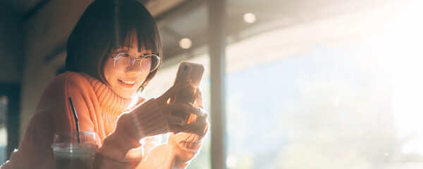 Young adult happy asian woman wear eyeglasses using mobile phone for social media application...