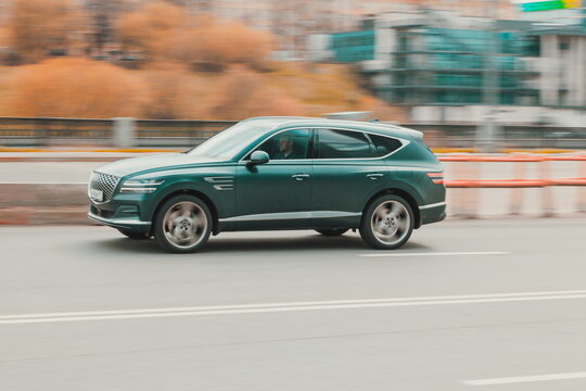Green premium class SUV genesis gv80 at the city street in motion