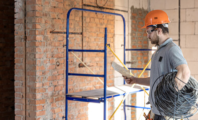 An electrician contractor examines a blueprint at a construction site.
