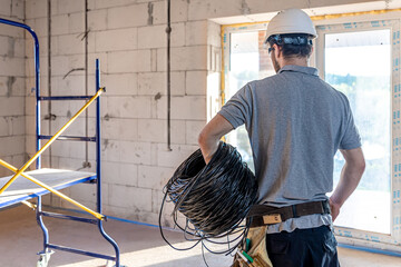 An electrician contractor examines a blueprint at a construction site.