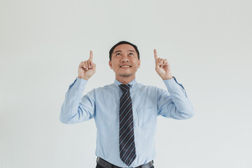 Portrait of sales man wearing blue shirt and tie pointing up on empty space for advertisement or idea
