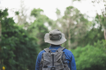 Young man with a backpack is walking alone the road. Man is looking forward to an interesting travelling.