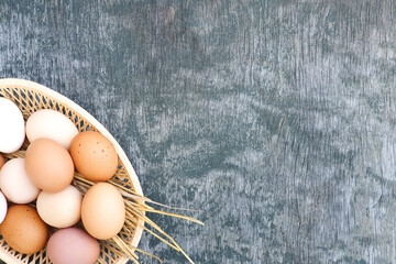 White and red brown eggs of domestic hens in basket on old wooden texture background. Natural eggs. Copy space, top view.