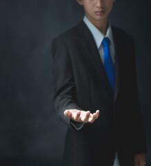 Young businessman portrait on black background.