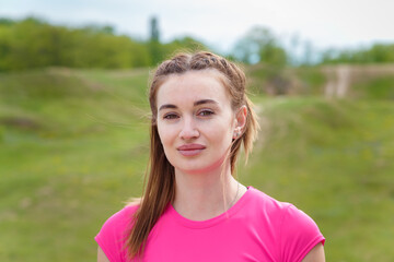 Portrait of young smiling woman in sportswear outdoors getting ready for physical training.
