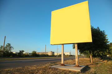 A large yellow billboard stands on the side of the road.
