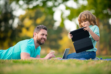 Father and son online learning. Concept of friendly family. Kid with a laptop outdoors in the summer. Child in a park on distance learning.