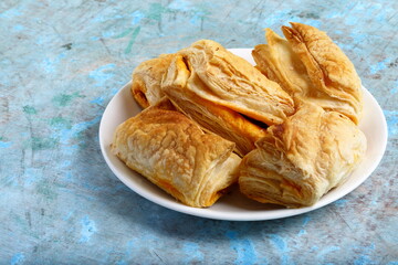 Oven fresh chicken curry puffs on a rustic kitchen table background.