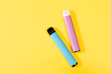 disposable electronic cigarettes with shadow on a yellow background with copy space. The concept of modern smoking, vaping and nicotine. top view.