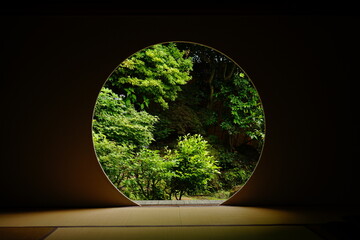 Looking at Japanese garden thru Round window in Japanese architecture -...