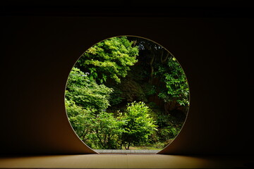 Looking at Japanese garden thru Round window in Japanese architecture -...