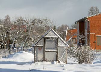 fresh snow covers the surroundings and the greenhouse in the garden, snow-textured surfaces