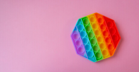 popular silicone colorful anti-stress toy Pop It in the shape of a hexagon on a pink background. Click Pop Bubble. Cheerful childrens game.Place for text