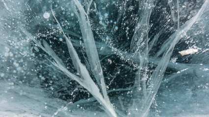 Turquoise ice close-up, detailed. The surface is lined with intersecting deep cracks. Bubbles of frozen methane gas are visible in the ice mass. Full screen. Baikal