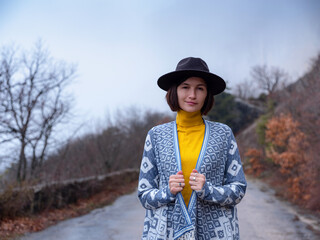 Stylish hipster woman in a hat walking down a mountain road