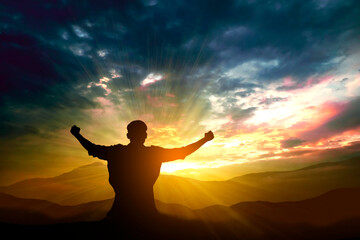 silhouette of man rising hands on mountain in morning with vintage light