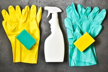 Yellow, green sponges, rubber gloves, cleaner spray bottle on a gray concrete background. House cleaning service and housekeeping concept. Flat lay, copy space. Cleaning supplies.