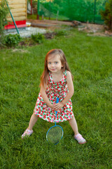 A girl with a racket on a green lawn. badminton. Active holidays in the summer. vacation. Vertical....