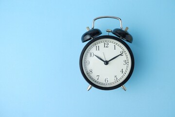 black alarm clock isolated on blue background