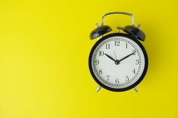 black alarm clock isolated on yellow background