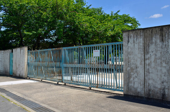 学校の門は警備中で閉じられている　看板には「警備中」と書いてある。