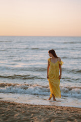 Young woman enjoying beautiful sunset on the beach. Feminine, attractive and sensual silhouette. Travel, weekend, relax and lifestyle concept.