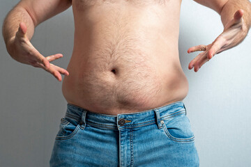 a man in blue jeans bared a big fat belly and spreads his hands