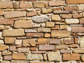 Texture rubble masonry made of uneven stone bricks. Background of the wall of the historical castle in the Crimea. Yellow brickwork of the fortress ruins.