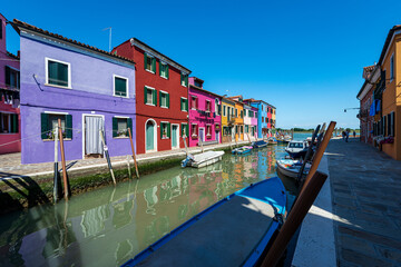 Fototapeta na wymiar Burano island, Venice lagoon. Canal with small boats moored and beautiful multi coloured small houses (bright colors). UNESCO world heritage site, Veneto, Italy, Europe. On the horizon Torcello island