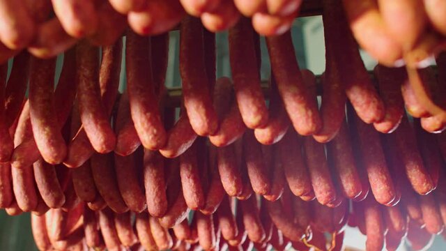 Meat delicacies on the metal frame. The production technology of sausage and smoked meat. Appetizing smoked. Tasty food and groceries. Cooking delicious . Salami. Meal Factory. Rows of ham.