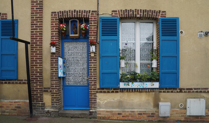 Picturesque facade of a traditional house. The door and window have a red brick border. The door...