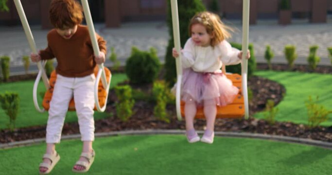 cute kids having fun on swings at the playground