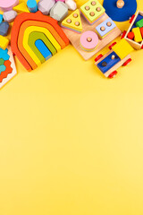 Baby kids toys frame. Educational wooden plastic and fluffy toys for children on yellow background. Top view, flat lay